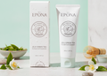 Epona Jeu Green Tea Flower Foam Cleanser shown with its white box and matching squeeze tube, styled on a light marble surface with green tea leaves, white flowers, and a bamboo whisk against a mint and white background. A blue 'First in Canada' banner appears in the top right.